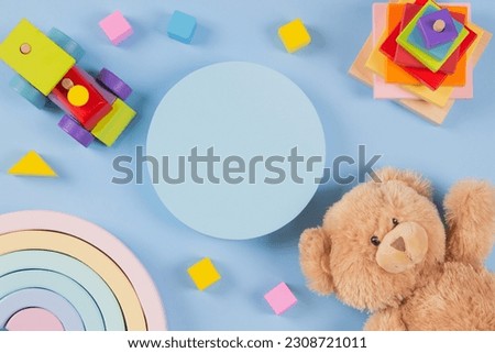 Empty round platform podium stand for product presentation, teddy bear and natural wooden toys on light blue background. Sustainable, Montessori educational toys for babies kids. Top view, flat lay