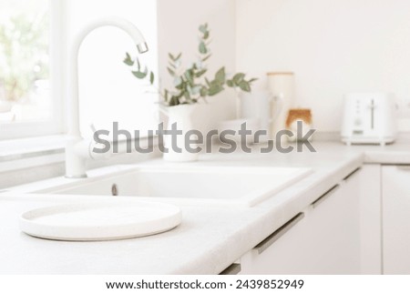 Empty round tray for product display on blurred kitchen sink counter and window sill background