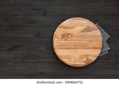 Empty Round Wooden Board On Black Wooden Kitchen Table, Top View, Copy Space. Wooden Platter, Copy Space.