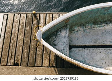 Empty rowboat tied to a wooden dock resting on water - Powered by Shutterstock