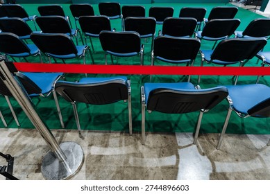 Empty Rows Of Chairs Behind Red Rope, Folding Plastic Seats Arranged In Neat Layout On Polished Concrete Floor, Stanchion Cordon Blocking Access, Anticipatory Mood Of Postevent Cooldown Or Preevent