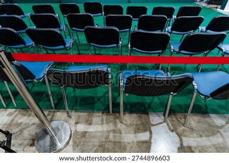 Empty Rows Of Chairs Behind Red Rope, Folding Plastic Seats Arranged In Neat Layout On Polished Concrete Floor, Stanchion Cordon Blocking Access, Anticipatory Mood Of Postevent Cooldown Or Preevent
