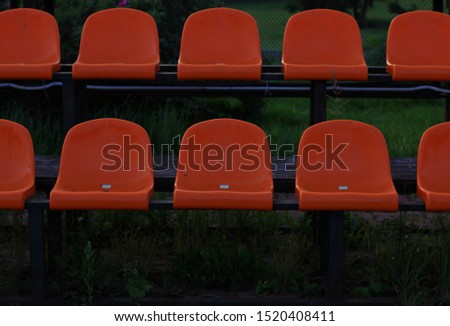 empty rows of orange seats or chairs for fans at a street football stadium