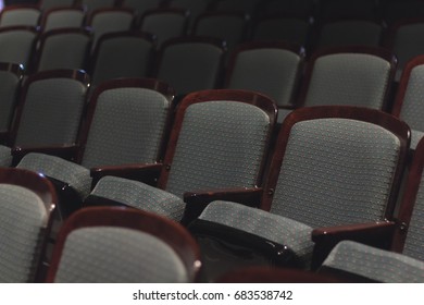 Empty Rows of Padded Wooden Chairs with Dim Soft Light in Auditorium or Theatre