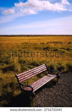 An empty rustic bench on the meadow footpath at Seljalandsfoss Waterfall in Iceland