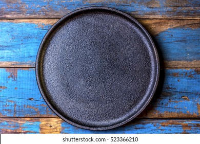 Empty Rustic Black Cast Iron Plate Over Old Wooden Blue Background