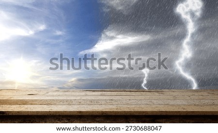 Empty rustic wooden table with a background of contrasting weather, showing a bright sunny sky on one side and a dark stormy sky with rain and lightning on the other