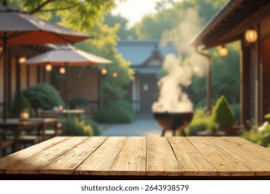 Empty rustic wooden table with copy space in a sunny summer garden. In the background barbecue grill garden umbrella and cozy holiday cabin. Outdoor party, grilling time and summer relaxation concept.