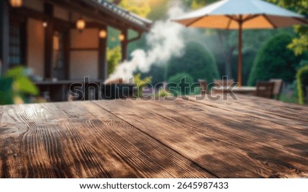 Empty rustic wooden table with copy space in sunny summer garden with small garden house background. Outdoor party, grilling time, summer relaxation concept. Mockup for food drink or seasonal product.
