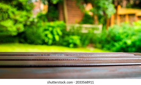 Empty rustic wooden table, selective focus foreground, and defocused lush green garden in background. Ideal for product display on top of the table.