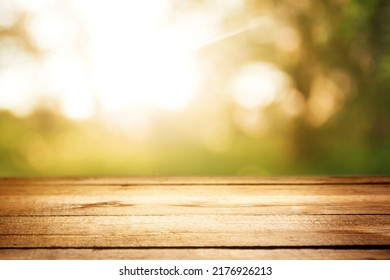 Empty Rustic Wooden Texture Of Old Wood Table Top, Blur Against Green Park With Defocused Sunlight, Blurred Foliage Backyard Background. Display Mock Up, Montage Your Product, Design Key Visual Layout