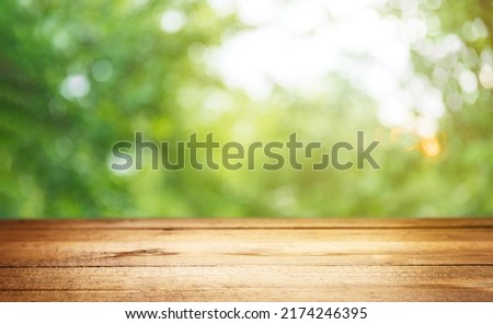 Empty rustic wooden texture of old wood table top, blur against green park with defocused sunlight, blurred foliage backyard background. Display mock up, montage your product, design key visual layout