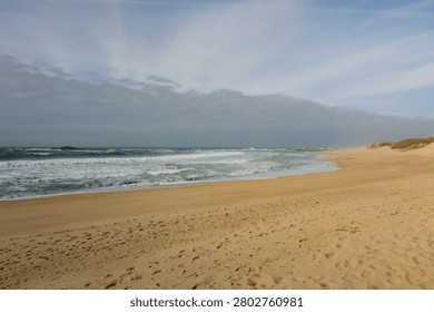Empty sandy beach displaying ocean waves on a cloudy day
