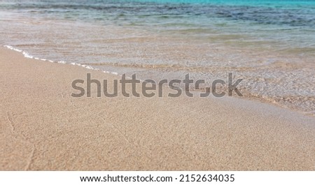 Empty sandy beach in Greece, close up view. Sea water touch wet white sand, view from above, copy space. Sunny day, summer holiday, Greek island.