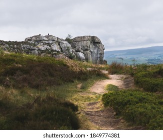 An empty sandy pathway leading towards the cow and calf rock outcrop in Ilkley, Yorkshire