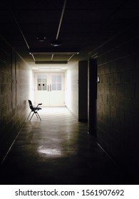 An Empty School Chair Leaning Against A Wall In A Dark, Forboding Classroom Hallway