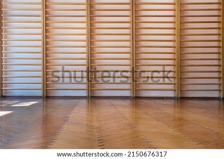 Empty school gym with parquet floor and wooden ladder fixed on concrete wall front view indoor