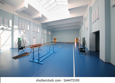 Empty School Gymnasium With Blue Floor And Gymnastic Apparatus.