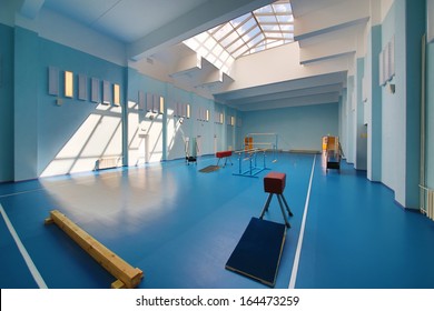 Empty School Gymnasium With Blue Floor And Exercise Equipment.