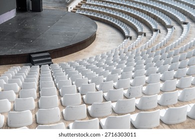Empty seating area facing a stage in an outdoor venue during a sunny day