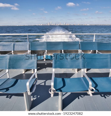 Empty seats in the back of a ferry on a sunny day with the St. Petersburg, Florida skyline on the horizon.