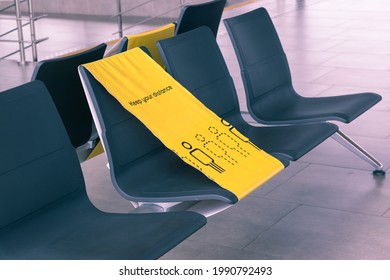 Empty seats in the departure area at the airport during a covid-19 pandemic. Picture of social distance at the airport. The yellow banner line divides seats into safe spaces. Sign - keep your distance