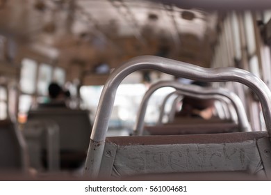 Empty seats inside a low-budget bus with unclear writing/ markings on the seat