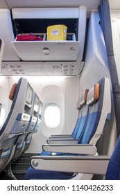 A Empty Seats On An Airplane Under An Open Box With A Bag With A Crew Demo Kit. Overhead Compartment With Emergency Set - Airplane Cabin Interior.