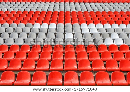 Empty seats in the stands of the arena or auditorium. Rows of red and white stadium seats without spectators. The concept of the abolition of sports and mass entertainment events