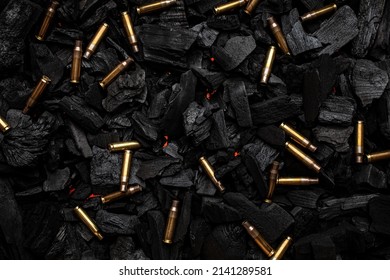 Empty shells from weapons on black smoldering coals. Consequences of the war. Dark background.