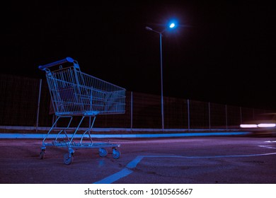 Empty Shopping Cart On The Lonely Parking Lot At Night