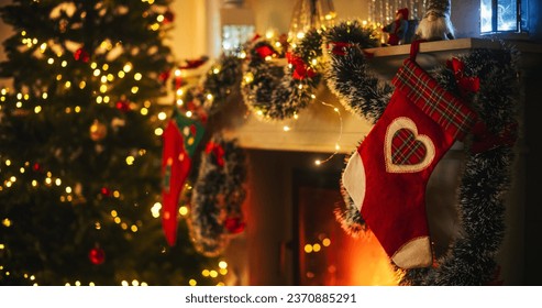 Empty Shot Depicting the Magic of Holidays on a Peaceful Snowy Christmas Eve: Close Up on Decorated Fireplace with Stockings Next to a Christmas Tree. Green and Red Garlands, Ribbons and Lights - Powered by Shutterstock