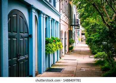 Empty sidewalk view of lush summer greenery lining the colorful Georgian architecture of the colonial Rainbow Row in the historical Battery neighborhood of Charleston, South Carolina, USA