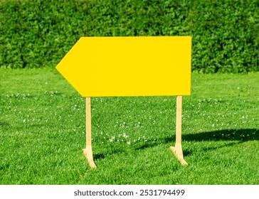 Empty sign. yellow pointer stands on green grass in the park. Mockup arrow pointing left