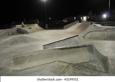 Empty Skate Park At Night With Grind Rails. Concrete Cement.