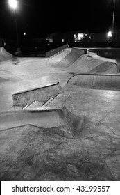 Empty Skatepark At Night With Grind Rails. Concrete Cement. This Is A Black And White Image