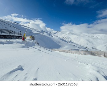 Empty ski slopes on a sunny winter day in a snowy mountain ski resort.