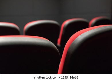 Empty Small Movie Or Cinema Theater Auditorium With Red Cinema Or Movie Seats Or Chairs From Behind Or Rear. Interior Of A Small Cinema Or Movie Theater Seats Or Chairs In The Back