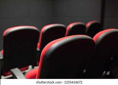 Empty Small Movie Or Cinema Theater Auditorium With Red Cinema Or Movie Seats Or Chairs From Behind Or Rear. Interior Of A Small Cinema Or Movie Theater Seats Or Chairs In The Back