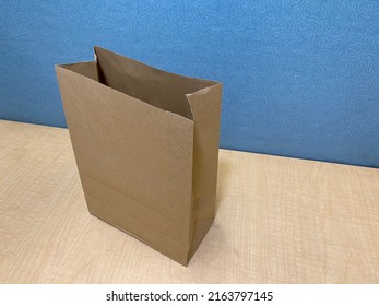 An Empty Small Typical Light Brown Paper Bag Sitting On An Office Cubicle.