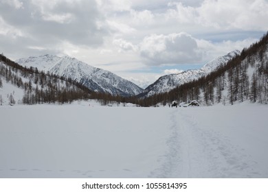 Empty snow path in valley surrounded by snow capped mountains. 