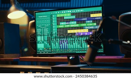 Empty soundproof control room in professional recording studio, stereo equipment with sliders and faders on panel board. Professional post production space with audio recording software.