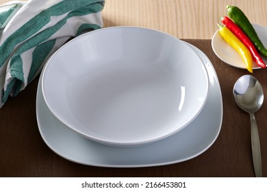 Empty Soup Plate With Chilli Peppers And One Spoon 