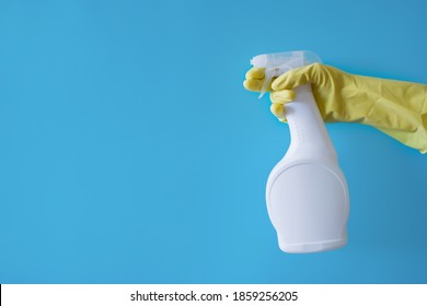 Empty space for text. Cleaning agent in a hand in a yellow glove on a blue background - Shutterstock ID 1859256205