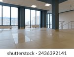 An empty spacious room of a modern office building with large windows. An empty hall with columns and a new renovation. Interior design. Suspended ceiling and square LED lamps.