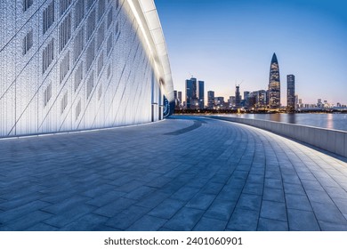 Empty square floor and brick wall buildings with city skyline in Shenzhen at night, China.