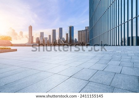 Empty square floor and glass wall with modern building at sunrise