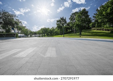 Empty square floor with green trees and blue sky sun background in the park.