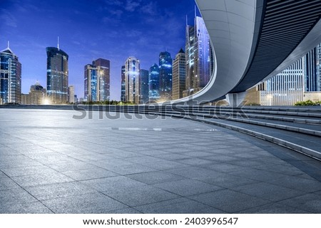 Empty square floor and pedestrian bridge with modern city commercial buildings at night in Shanghai, China.