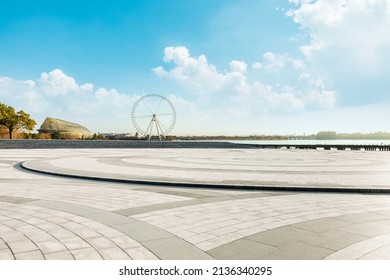 Empty square floor and playground ferris wheel with sky clouds